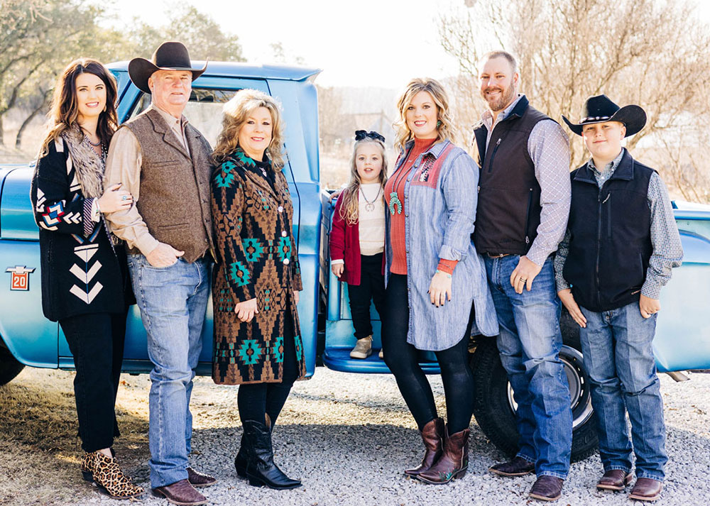 A group photo of Shelbi’s family posing next to a turquoise colored truck, posing and smiling.
